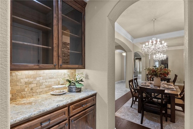 5104 Stonewater Loop, College Station, TX 77845 - dining space featuring arched walkways, crown molding, a chandelier, and wood finished floors