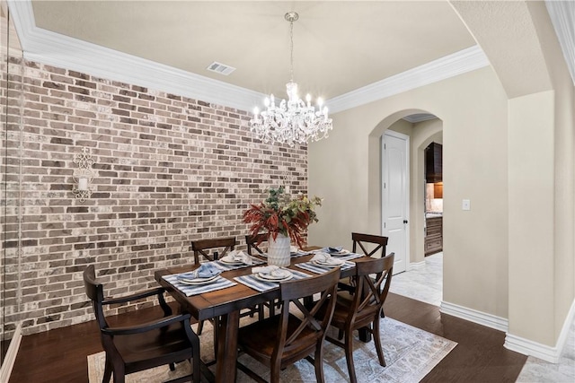 5104 Stonewater Loop, College Station, TX 77845 - dining area featuring arched walkways, a chandelier, dark wood finished floors, ornamental molding, and brick wall