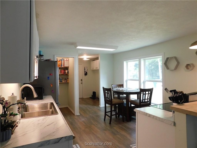 1117 Sycamore St, Navasota, TX 77868 - kitchen with a sink, dark wood-style floors, light countertops, white cabinetry, and baseboards