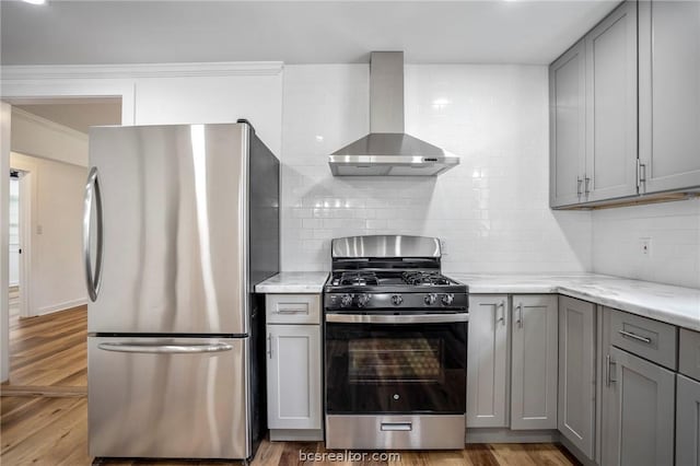 kitchen with wall chimney exhaust hood, gray cabinets, appliances with stainless steel finishes, and light hardwood / wood-style flooring