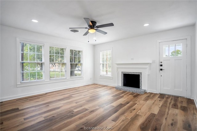 unfurnished living room featuring a wealth of natural light, hardwood / wood-style floors, and ceiling fan