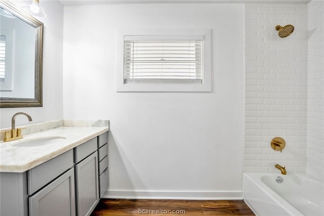 bathroom with hardwood / wood-style flooring, tiled shower / bath combo, and vanity