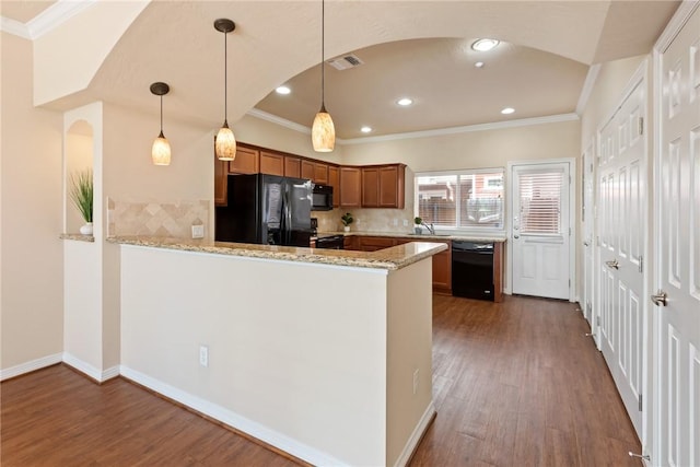 kitchen featuring brown cabinets, dark wood-type flooring, a sink, a peninsula, and black appliances