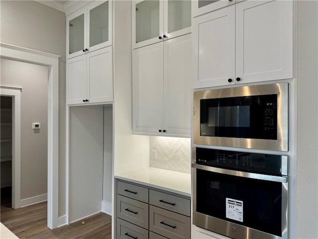 kitchen with built in microwave, stainless steel oven, and white cabinets