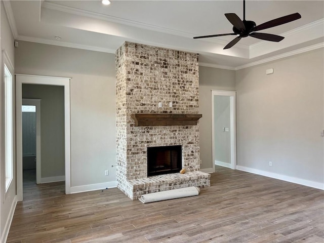 unfurnished living room featuring a raised ceiling, crown molding, and light wood-type flooring