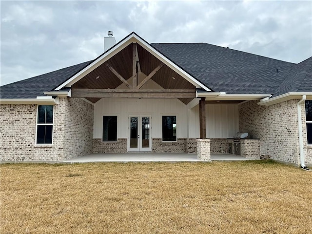 rear view of house featuring french doors, area for grilling, a patio area, and a lawn