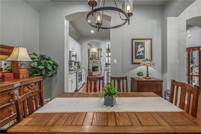 dining room with an inviting chandelier, a fireplace, and vaulted ceiling