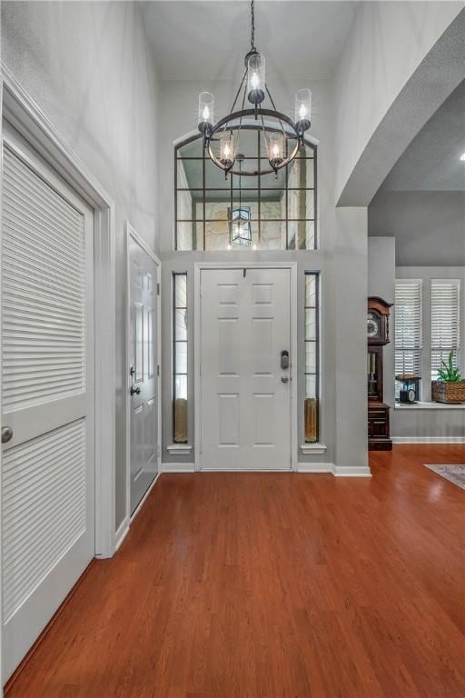 foyer with an inviting chandelier, wood-type flooring, and a high ceiling