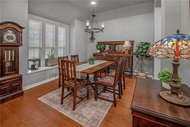 dining room featuring an inviting chandelier, light hardwood / wood-style flooring, and lofted ceiling