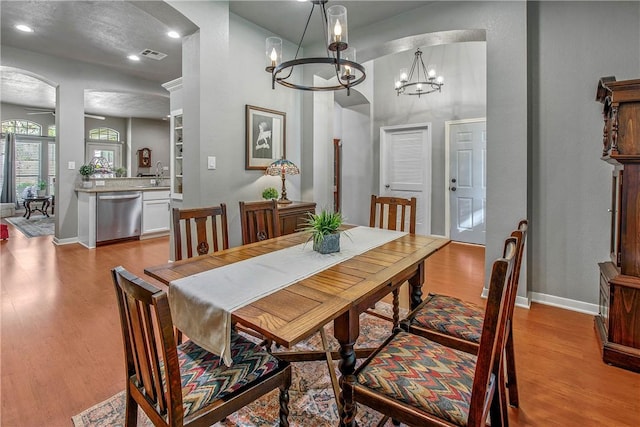 dining area with an inviting chandelier, sink, and light hardwood / wood-style floors