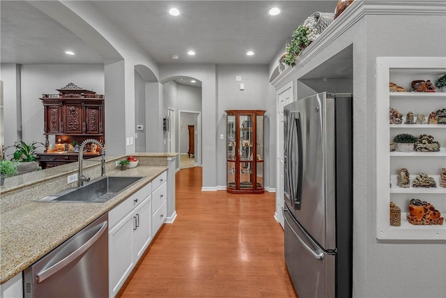 kitchen featuring sink, light hardwood / wood-style flooring, built in features, stainless steel appliances, and white cabinets