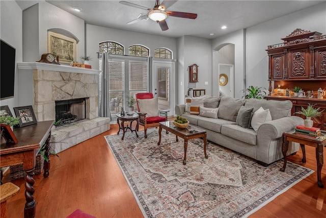 living room featuring ceiling fan, a fireplace, and light hardwood / wood-style flooring