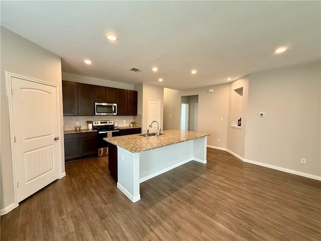4704 Los Pines Way, Bryan, TX 77807 - kitchen featuring stainless steel appliances, dark wood finished floors, a sink, a kitchen island with sink, and dark brown cabinets