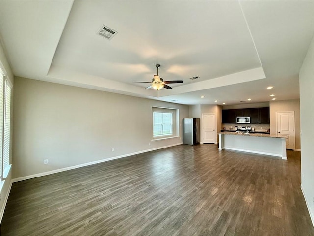 4704 Los Pines Way, Bryan, TX 77807 - unfurnished living room featuring a tray ceiling, baseboards, dark wood-style floors, and recessed lighting