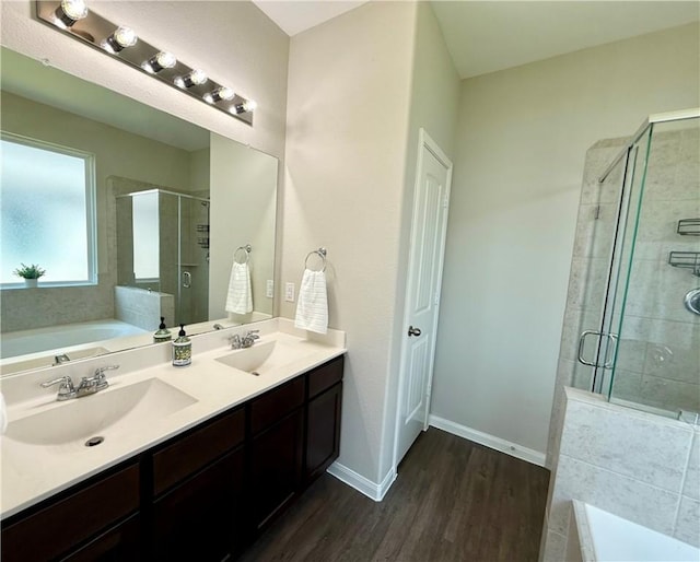 4704 Los Pines Way, Bryan, TX 77807 - bathroom featuring a bath, a stall shower, wood finished floors, baseboards, and double vanity
