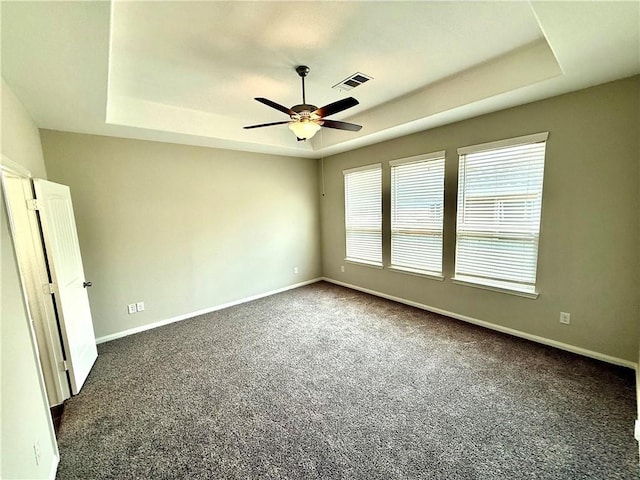 4704 Los Pines Way, Bryan, TX 77807 - empty room featuring a tray ceiling, dark colored carpet, a ceiling fan, and baseboards