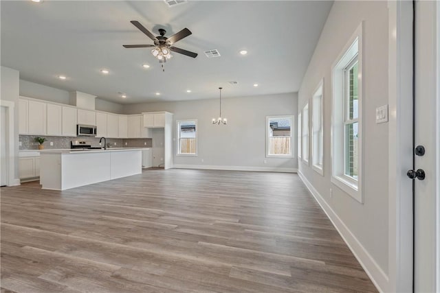 kitchen featuring an island with sink, white cabinets, stainless steel appliances, and light hardwood / wood-style floors