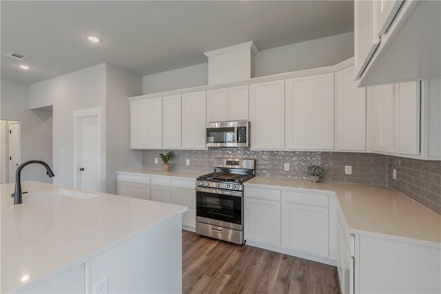 kitchen with white cabinetry, sink, tasteful backsplash, hardwood / wood-style floors, and appliances with stainless steel finishes