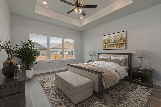 bedroom featuring ornamental molding, hardwood / wood-style flooring, ceiling fan, and a tray ceiling