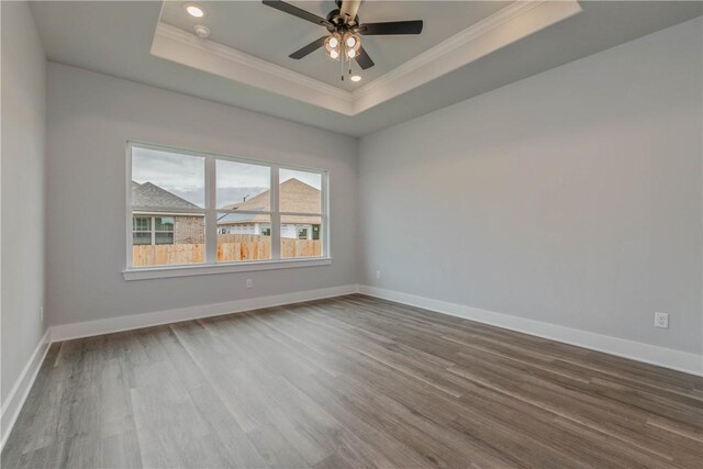 spare room with a raised ceiling, crown molding, ceiling fan, and hardwood / wood-style flooring