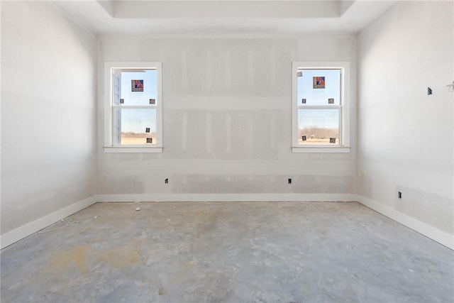 unfurnished room with a wealth of natural light, concrete floors, and a raised ceiling