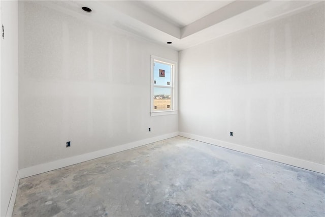 empty room with concrete flooring and a raised ceiling