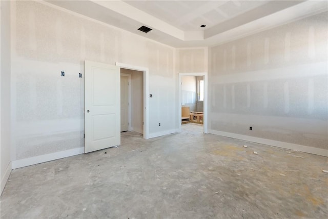 spare room featuring a tray ceiling and concrete flooring