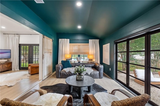 living room featuring french doors, vaulted ceiling, and light wood-type flooring