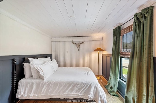 bedroom featuring hardwood / wood-style floors, wooden ceiling, and ornamental molding