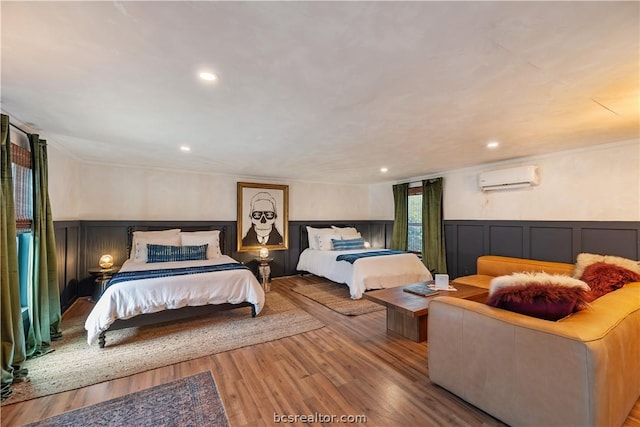 bedroom featuring a wall mounted air conditioner, light hardwood / wood-style flooring, and crown molding