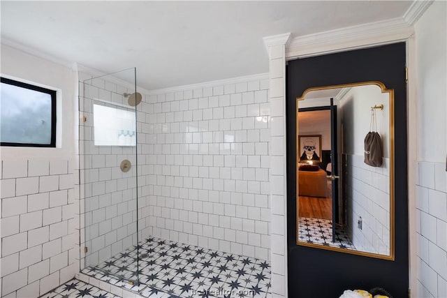 bathroom featuring a tile shower, crown molding, tile patterned flooring, and tile walls