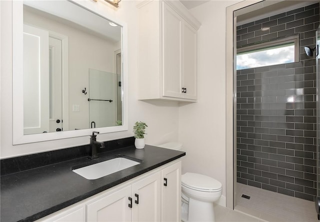 bathroom with a tile shower, tile patterned flooring, vanity, and toilet