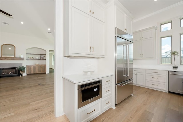 kitchen featuring white cabinets, crown molding, stainless steel appliances, and light hardwood / wood-style flooring