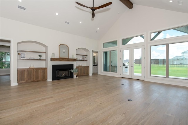 unfurnished living room featuring high vaulted ceiling, french doors, light hardwood / wood-style flooring, ceiling fan, and beam ceiling