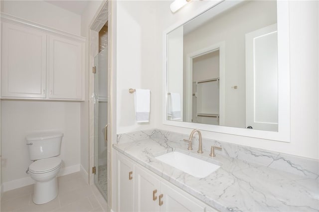 bathroom with toilet, vanity, tile patterned floors, and a shower with door