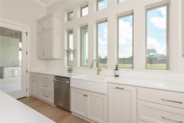 kitchen featuring white cabinets, light wood-type flooring, plenty of natural light, and sink