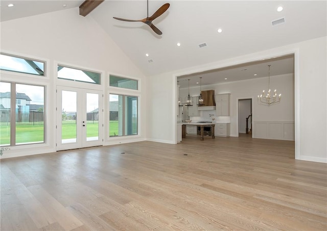 unfurnished living room featuring beamed ceiling, ceiling fan with notable chandelier, light hardwood / wood-style floors, and high vaulted ceiling