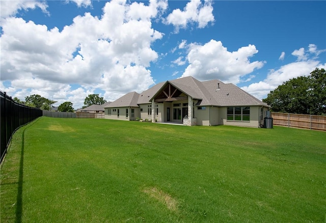 rear view of house with ceiling fan and a lawn