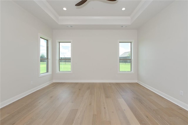 unfurnished room featuring a raised ceiling, ceiling fan, light hardwood / wood-style floors, and ornamental molding