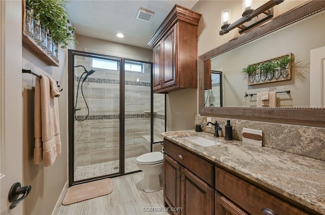 bathroom with wood-type flooring, vanity, toilet, and a shower with shower door