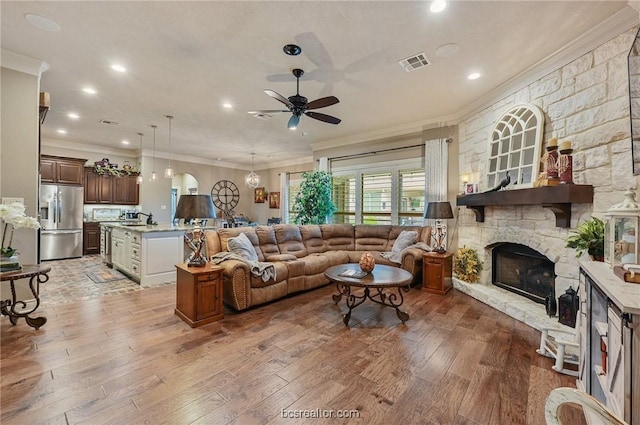 living room with ceiling fan, a fireplace, crown molding, and hardwood / wood-style flooring