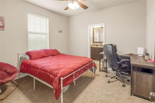 bedroom with ensuite bathroom, light colored carpet, and ceiling fan