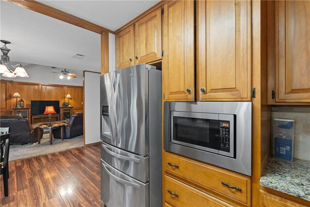 kitchen with stainless steel appliances, dark wood-style flooring, open floor plan, decorative backsplash, and light stone countertops