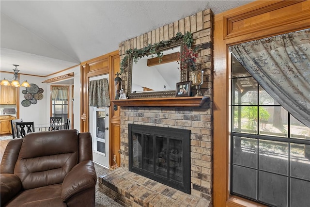 living room featuring lofted ceiling, a brick fireplace, and a chandelier