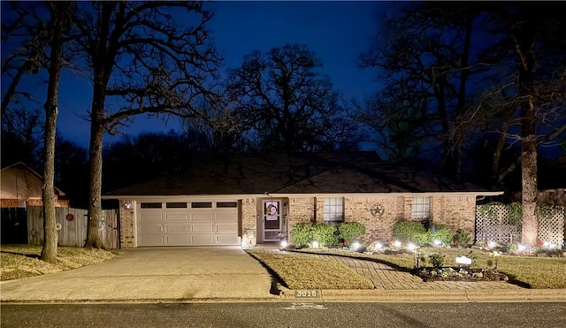 single story home with a garage, brick siding, fence, and driveway