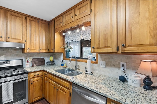 kitchen with appliances with stainless steel finishes, a sink, light stone countertops, extractor fan, and backsplash