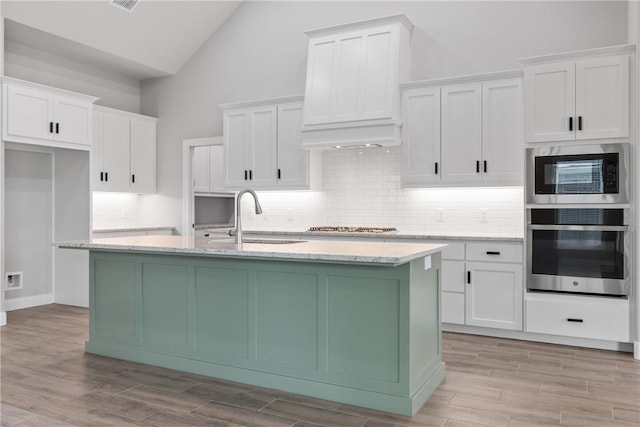2906 Spector Dr, Bryan, TX 77808 - kitchen with white cabinetry, tasteful backsplash, a sink, stainless steel appliances, and an island with sink