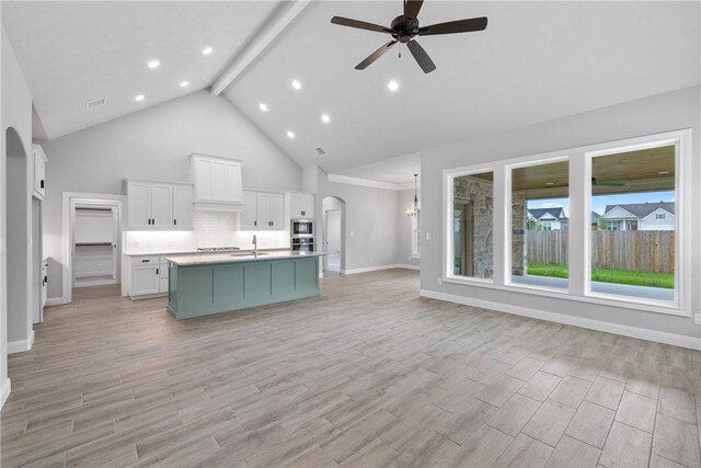 2906 Spector Dr, Bryan, TX 77808 - kitchen with ceiling fan, arched walkways, open floor plan, an island with sink, and high vaulted ceiling