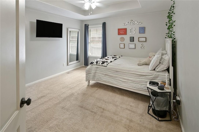 carpeted bedroom featuring ceiling fan and a raised ceiling