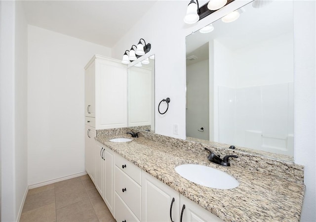 full bathroom with a sink, baseboards, double vanity, and tile patterned floors